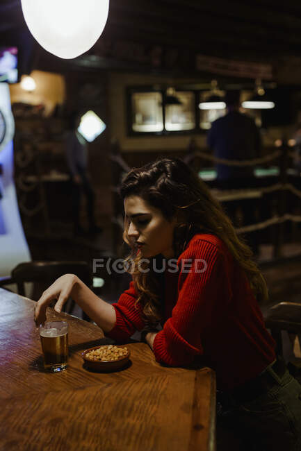 Грустная женщина среднего возраста с алкоголем и закусками на столе, сидящая в ресторане — стоковое фото