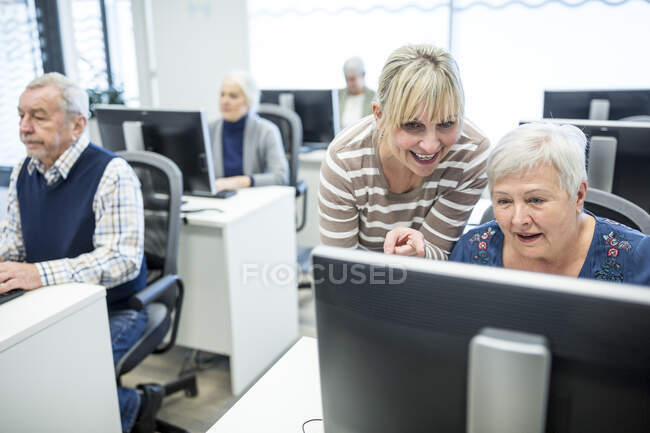 Anziani attivi che frequentano corsi di informatica, intrusi che danno consigli — Foto stock