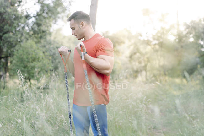 Hombre durante el entrenamiento con cuerdas de goma en el bosque - foto de stock