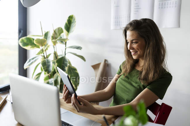 Усміхнена комерсантка користується цифровим планшетом у домашньому офісі. — стокове фото