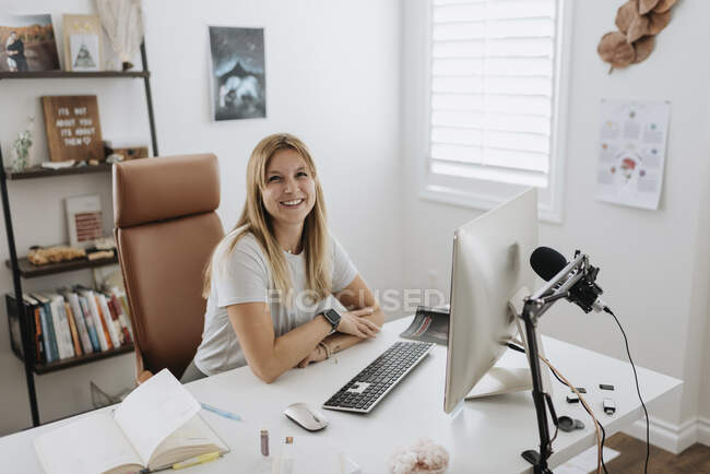 Femme d'affaires souriante utilisant un ordinateur sur le bureau à la maison — Photo de stock