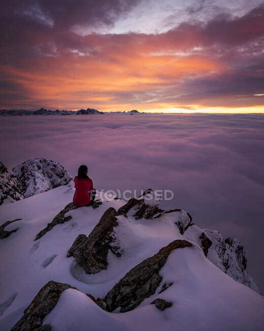 Жінка захоплюється похмурим заходом сонця з вкритої снігом вершини гори Аггенштайн. — стокове фото
