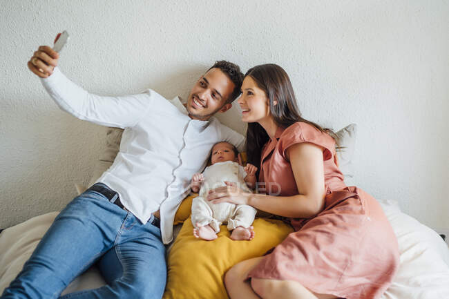 Felice genitori prendendo selfie con bambino in camera da letto a casa — Foto stock