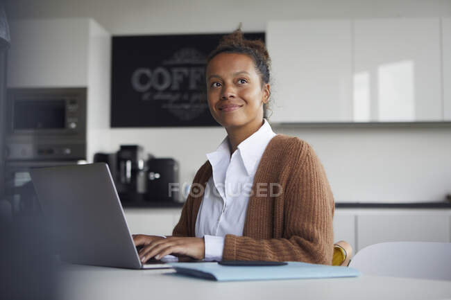 Portrait of smiling businesswoman working on laptop in kitchen — Stock Photo