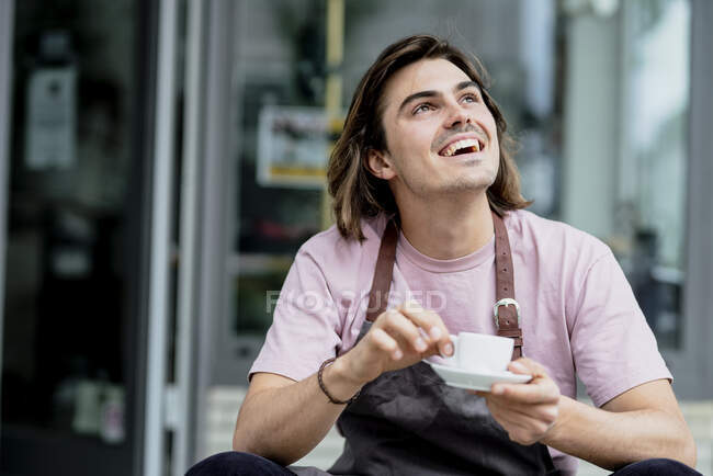 Männlicher Besitzer hält Kaffeetasse lachend vor Café — Stockfoto