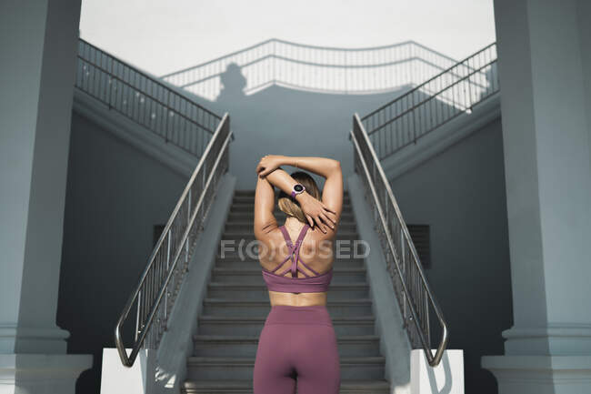 Молода жінка, стоячи перед сходами, простягає руки. — стокове фото