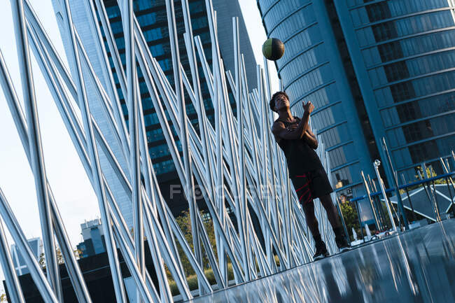 Giovane uomo che gioca a basket nella città moderna circostante — Foto stock