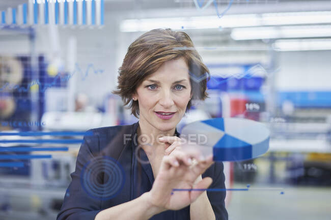 Female manager touching pie chart on glass in industry — Stock Photo
