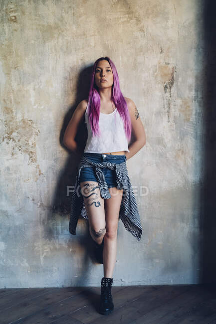 Ritratto di una giovane donna elegante con i capelli rosa appoggiata a un muro — Foto stock