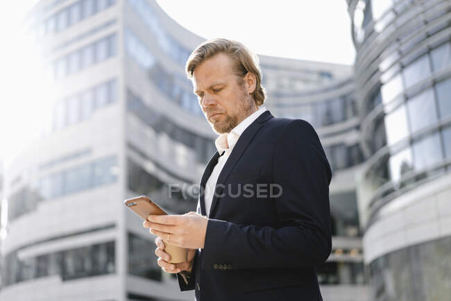 Бізнесмен користується смартфоном у місті. — стокове фото