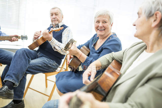 Старші у відставці вдома ходять на уроки гри на гітарі. — стокове фото