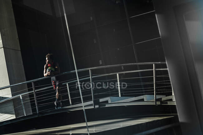 Молодой человек с баскетболом стоит в современном здании в городе — стоковое фото