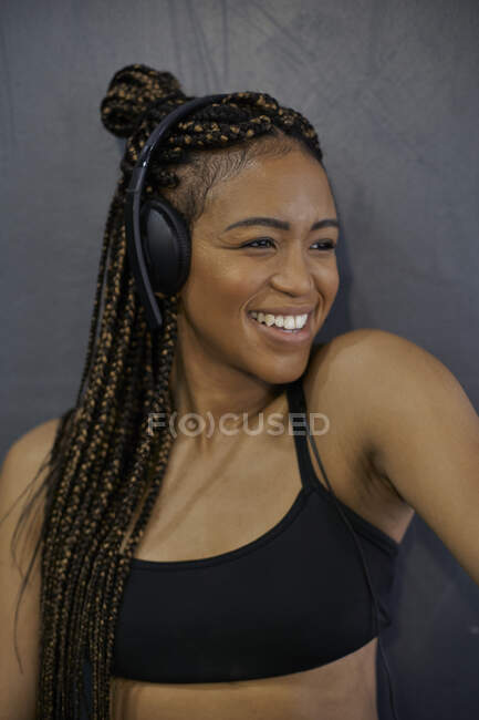 Primo piano dell'atleta sorridente che ascolta musica attraverso le cuffie in palestra — Foto stock