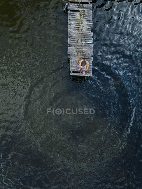 Vista aérea del hombre de pie en el borde del embarcadero de la orilla del lago - foto de stock