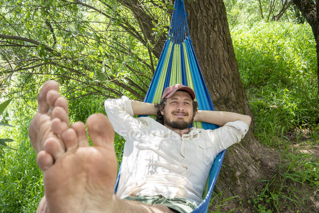 Чоловік відпочиває на гамаку в лісі — стокове фото