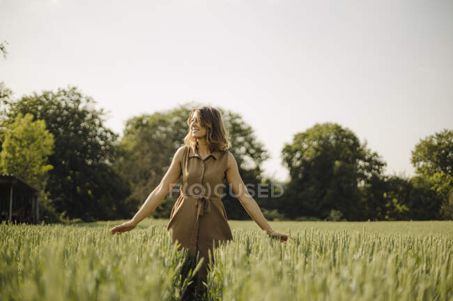 Jovem em um campo de grãos no campo tocando orelhas — Fotografia de Stock