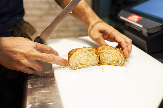 Baker cutting bread over kitchen counter at bakery — Foto stock