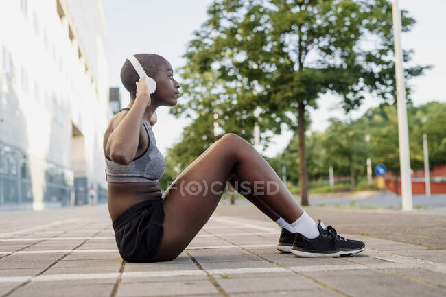 Mujer joven escuchando música mientras hace ejercicio en el sendero de la ciudad - foto de stock