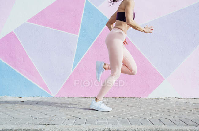 Femme courant dans la ville devant un mur coloré — Photo de stock