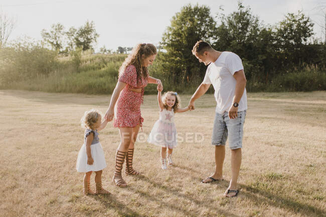 Eltern mit zwei Töchtern stehen auf einer Wiese — Stockfoto