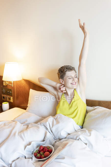 Розслаблена жінка з заплющеними очима розтягується на ліжку — стокове фото