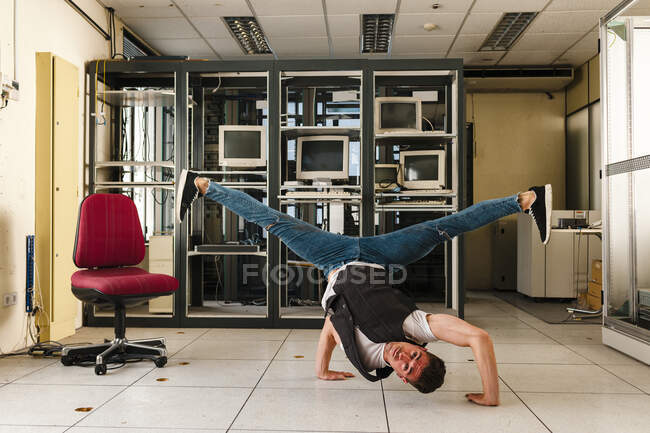 Dançarino masculino realizando acrobacias no chão em quarto abandonado — Fotografia de Stock