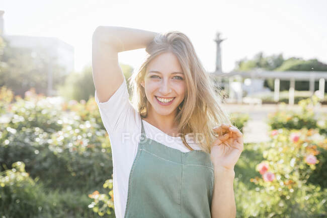 Porträt einer glücklichen jungen Frau im öffentlichen Garten bei Gegenlicht — Stockfoto