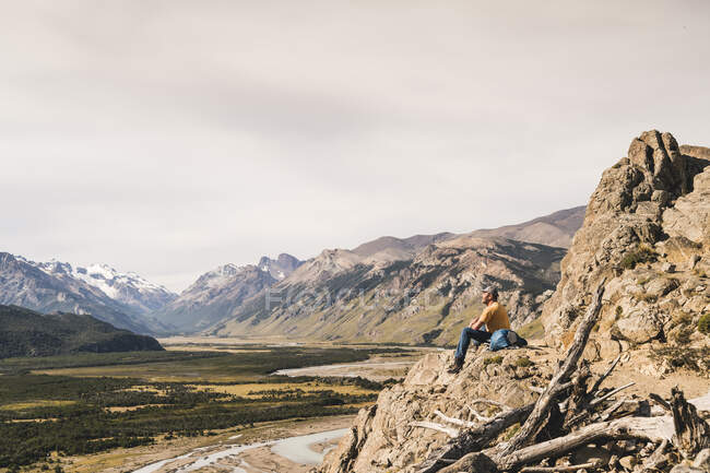 Männlicher Wanderer sitzt auf einem Felsen vor den Anden Patagoniens, Argentinien — Stockfoto