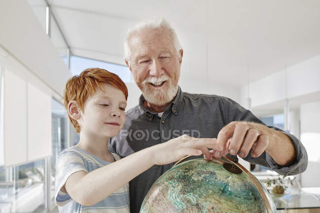 Grandfather and grandson looking at globe in a villa — Stock Photo