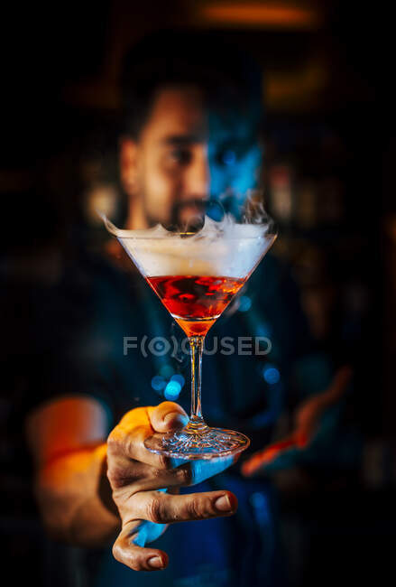 Primer plano del camarero masculino que celebra un cóctel en un club nocturno - foto de stock