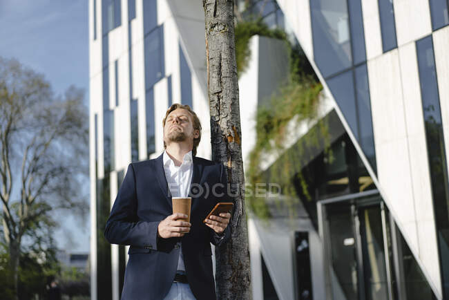 Бізнесмен з кавою та смартфоном у місті. — стокове фото