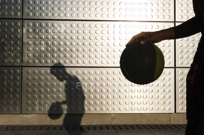 Young man playing basketball at a metallic shining wall — Stock Photo