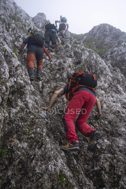 Male hikers with backpacks climbing on mountain, Bergamasque Alps, Italy — Stock Photo