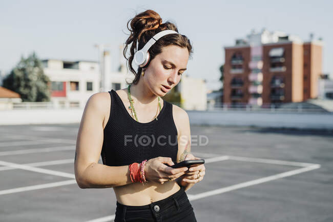 Woman wearing headphone using mobile phone outdoors — Stock Photo