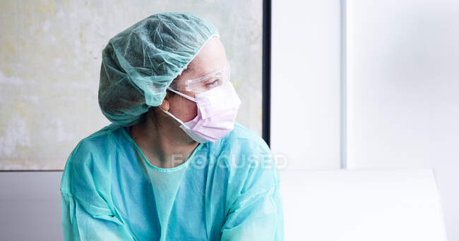 Primer plano de la doctora pensativa sentada contra la pared en el hospital - foto de stock