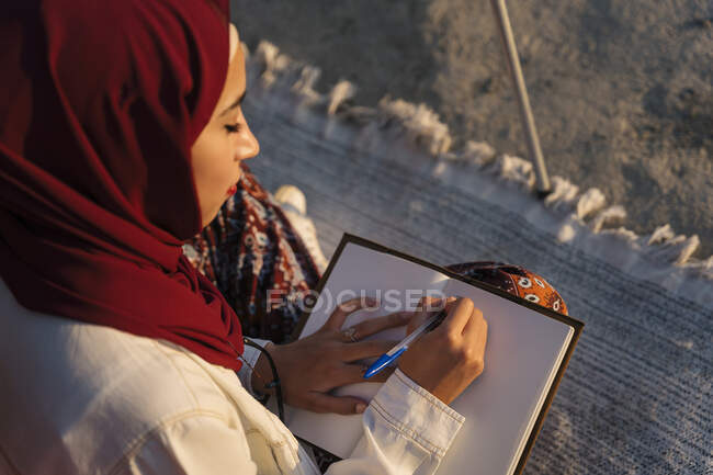 Young tourist woman wearing Hijab taking notes — Photo de stock
