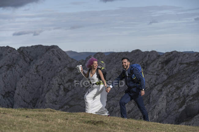 Coppia di sposi con zaini da arrampicata che camminano sul prato — Foto stock