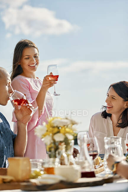 Jeune femme dînant avec des amis soulevant verre de vin — Photo de stock