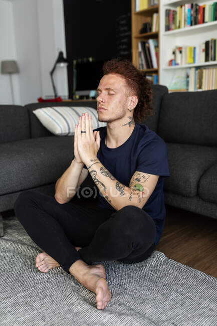 Чоловік молиться, сидячи на підлозі вдома — стокове фото