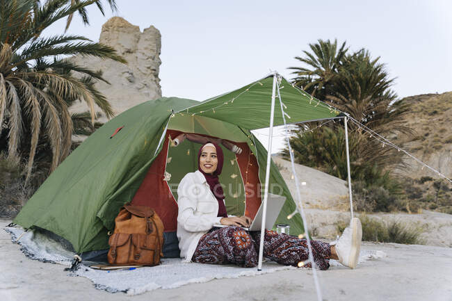 Young woman wearing Hijab using laptop at a tent — Stock Photo