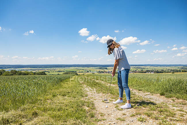 Молодая женщина играет в гольф в сельской местности — стоковое фото