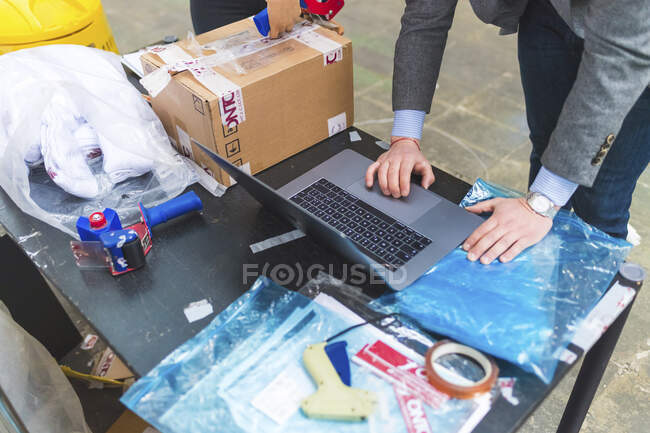 Businessman using laptop on table in a warehouse — Stock Photo