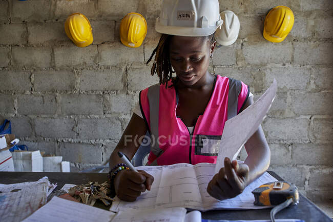 Imprenditore edile donna che analizza il progetto sulla scrivania mentre è seduta a scuola — Foto stock
