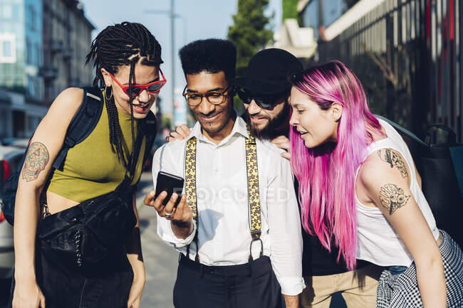 Grupo de amigos compartilhando smartphone na cidade — Fotografia de Stock