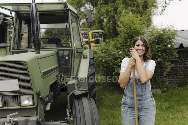 Portrait of a confident young woman standing at a tractor in the countryside — Stock Photo