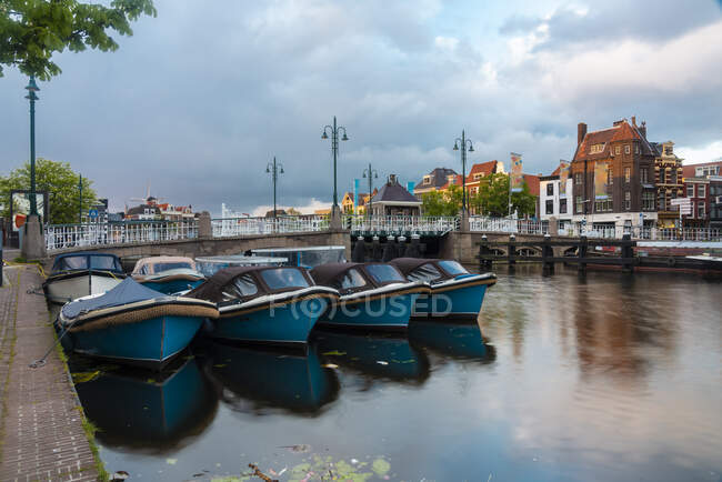 Нідерланди, Південна Голландія, Лейден, Моторні човни пришвартовані перед мостом у старій затоці Галгейвотер. — стокове фото