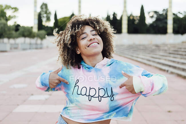Portrait of happy woman showing on imprint of her pullover — Stock Photo