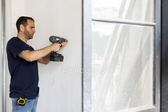 Construction worker using drill at a wall — Stock Photo