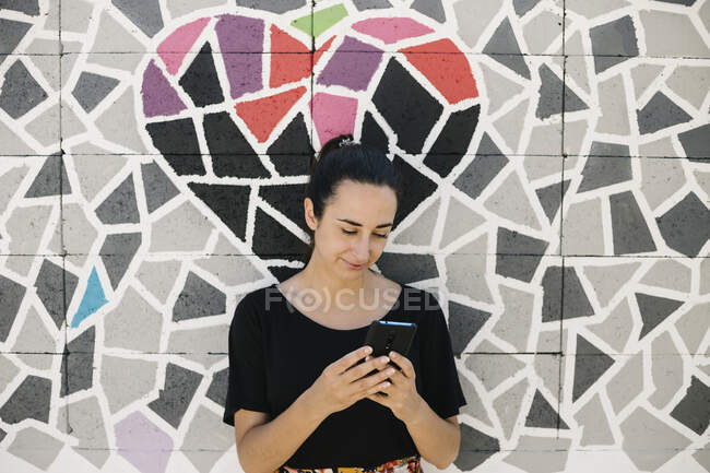 Портрет женщины с помощью смартфона перед красочной стеной — стоковое фото