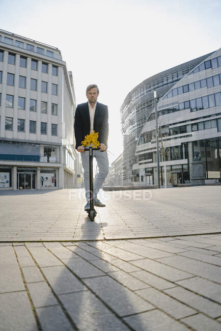 Бізнесмен з коктейлем і кучкою квітів у місті. — стокове фото